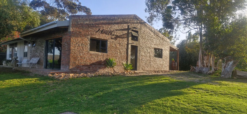 Exterior view of a rustic-style guesthouse with a brick facade, surrounded by green lawns and trees.