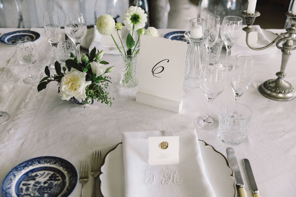 A beautifully set dining table featuring an elegant floral arrangement, crystal glassware, and fine china, with a table number displayed.