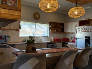 Modern kitchen featuring wooden accents, pendant lighting, and a spacious countertop with bar stools.
