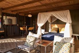 Stylish interior of a modern accommodation featuring a four-poster bed with a canopy, cozy seating area, and a small dining area.
